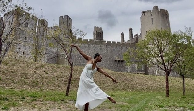 Jovanay dancing in a white dress on a lawn in front of a castle